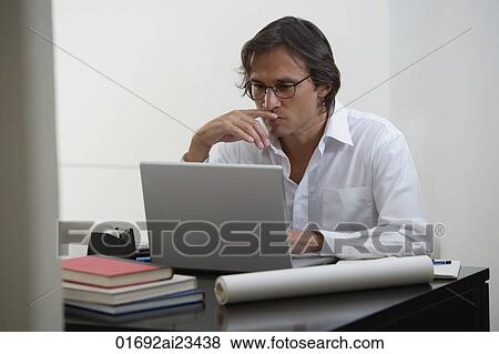 Businessman using laptop at the desk View Large Photo Image Stock Photo - Businessman using laptop at the desk. Fotosearch