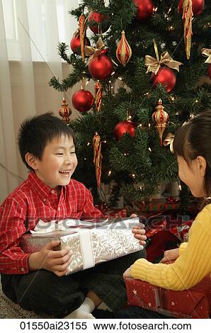 Children with presents sitting under Christmas tree View Large Photo Image Stock Photography - Children with presents sitting under Christmas tree. Fotosearch