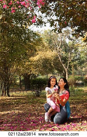 Picture - daughter sitting on mother's lap outdoors. Fotosearch