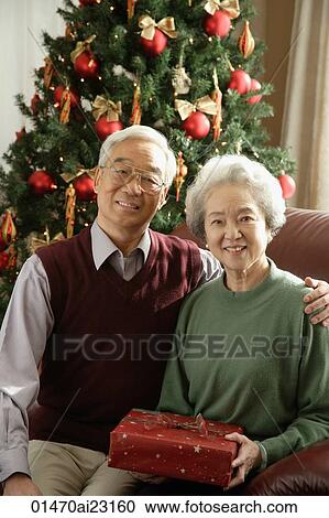 Stock Image - Elderly couple at Christmas time smiling at camera. Fotosearch