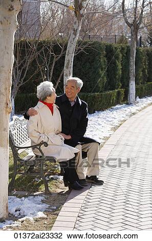 Elderly couple sitting on park bench View Large Photo Image Stock Image - Elderly couple sitting on park bench. Fotosearch