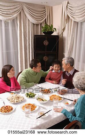 Family at dinner table having traditional food, boy standing next to grandfather View Large Photo Image Stock Photo - Family at dinner table having traditional food, boy standing next to grandfather. Fotosearch