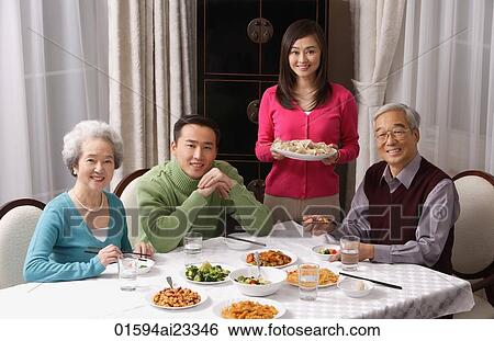Family at dinner table having traditional food View Large Photo Image Stock Photograph - Family at dinner table having traditional food. Fotosearch