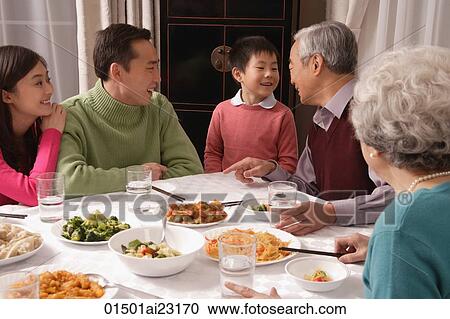 Family chatting over at dinner table having traditional food View Large Photo Image Stock Image - Family chatting over at dinner table having traditional food. Fotosearch