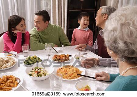 Family chatting over at dinner table having traditional food, boy standing next to grandfather View Large Photo Image Stock Photo - Family chatting over at dinner table having traditional food, boy standing next to grandfather. Fotosearch