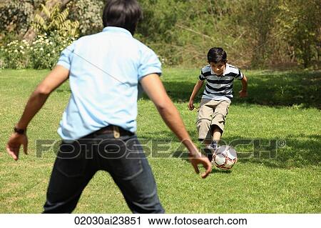 Father and son kicking soccer ball View Large Photo Image Stock Image - Father and son kicking soccer ball. Fotosearch