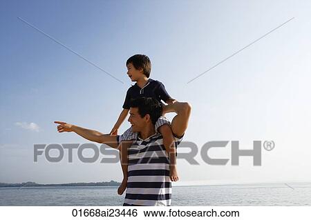 Stock Photograph - Father piggybacking son at the beach. Fotosearch