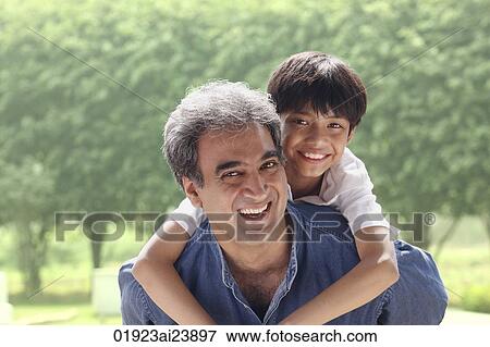 Father with son on his back, both smiling at camera View Large Photo Image Stock Photo - Father with son on his back, both smiling at camera. Fotosearch