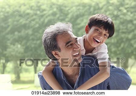Stock Photo - Father with son on his back, son smiling at camera. Fotosearch