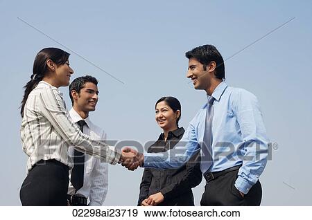 four business colleagues, two shaking hands View Large Photo Image Stock Photo - four business colleagues, two shaking hands. Fotosearch