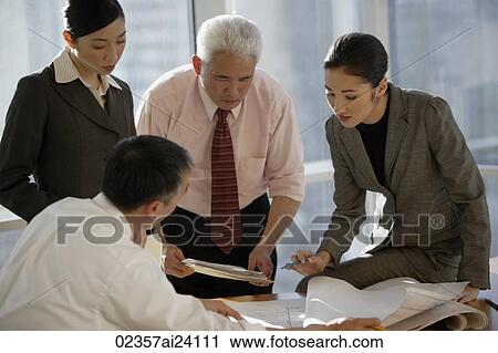 Stock Image - four colleagues discussing documents. Fotosearch