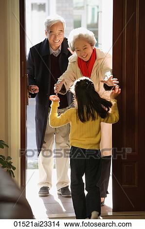 Picture - Girl greeting grandparents at door. Fotosearch