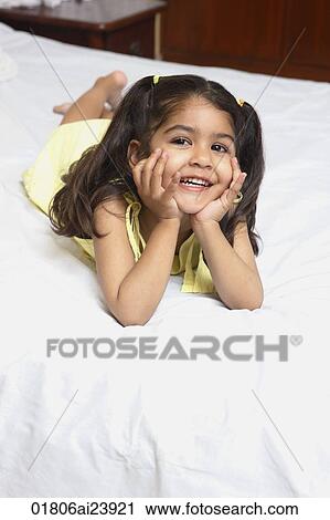 Girl lying on bed, chin in hands View Large Photo Image Stock Image - Girl lying on bed, chin in hands. Fotosearch