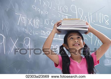 Stock Photo - girl with books stacked on head, looking up (horizontal). Fotosearch