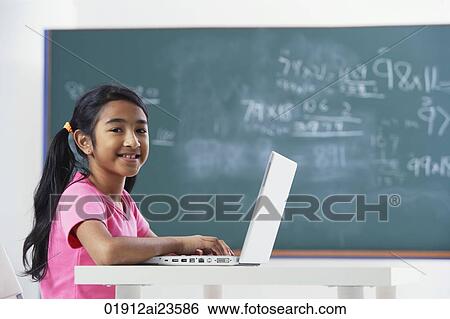 Stock Photograph - girl working at laptop, smiling at camera. Fotosearch