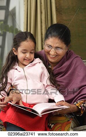 Stock Image - granddaughter sits on grandmother's lap for story (vertical). Fotosearch