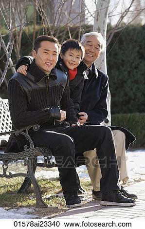 Stock Image - Grandfather, son and grandson in the park. Fotosearch