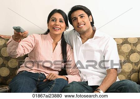 Stock Image - Husband and wife watching tv. Fotosearch