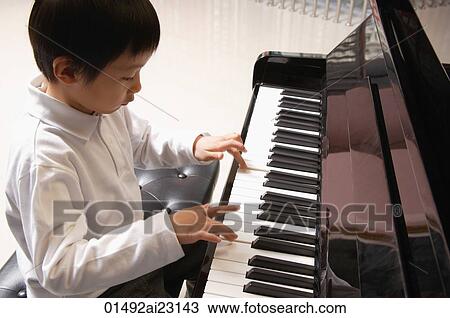 Stock Image - Little boy playing piano. Fotosearch