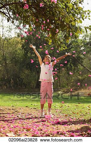 Stock Photo - Little girl in park, tossing blossoms in air. Fotosearch