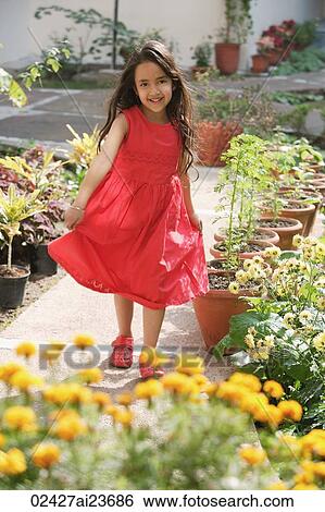 Stock Photograph - little girl in red dress standing among potted flowers. Fotosearch