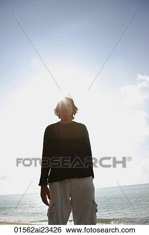 Man at the beach with water and skyline background View Large Photo Image Stock Photograph - Man at the beach with water and skyline background. Fotosearch