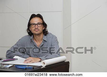 Man sitting at desk with pencil and paper, looking at camera View Large Photo Image Stock Photo - Man sitting at desk with pencil and paper, looking at camera. Fotosearch