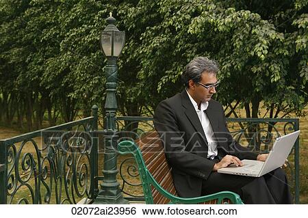 Stock Photograph - man with laptop on bench. Fotosearch