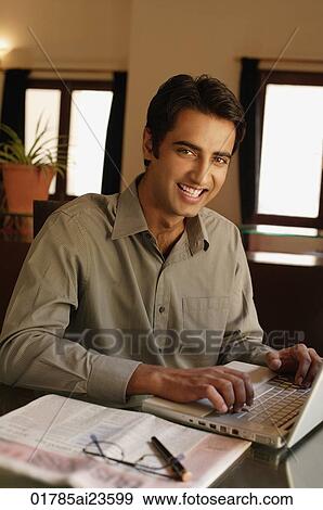 Stock Photo - man working at laptop, smiling at camera. Fotosearch