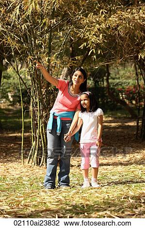 Stock Image - Mom showing daughter something in park. Fotosearch