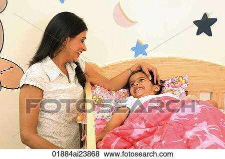 Mom tucking daughter into crib View Large Photo Image Stock Photo - Mom tucking daughter into crib. Fotosearch
