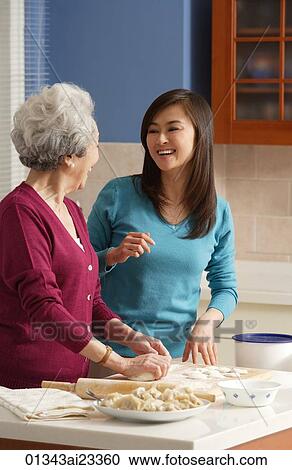 Stock Image - Mother and daughter baking in the kitchen. Fotosearch