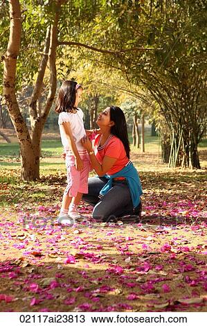 Stock Image - Mother and daughter in grove of trees. Fotosearch
