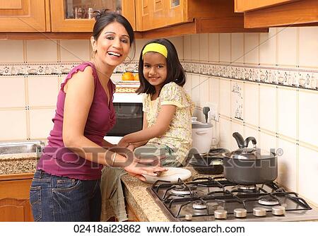 Stock Image - Mother and daughter in kitchen. Fotosearch