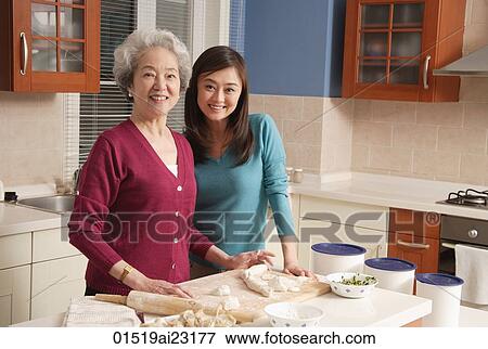 Stock Photo - Mother and daughter making dumplings in the kitchen. Fotosearch
