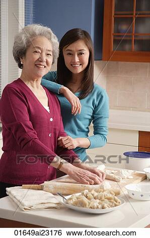 Stock Photograph - Mother and daughter making dumplings in the kitchen. Fotosearch