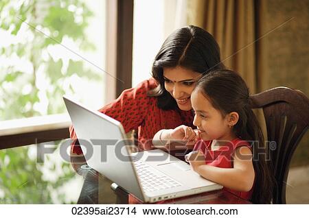 Picture - mother and daughter working at laptop (horizontal). Fotosearch