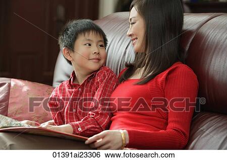 Mother and son looking at children's book View Large Photo Image Stock Photograph - Mother and son looking at children's book. Fotosearch