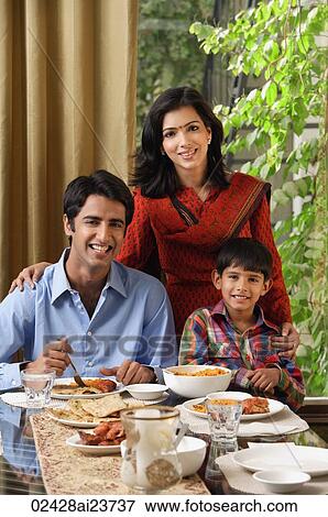 Stock Photo - mother and son stand near sitting father at dinner table. Fotosearch
