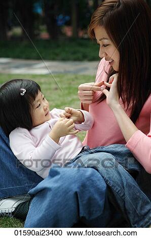 Mother on the ground paying with young daughter sitting on lap View Large Photo Image Stock Image - Mother on the ground paying with young daughter sitting on lap. Fotosearch