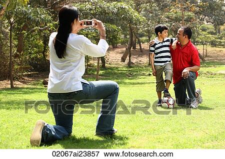 Stock Photo - Mother taking photo of father and son. Fotosearch