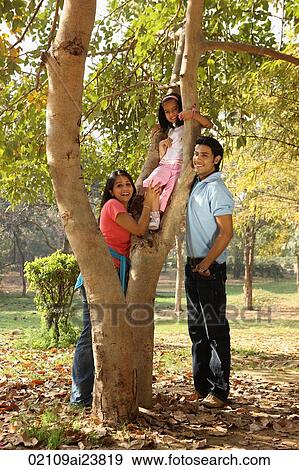 Stock Photo - Parents at park, daughter in tree. Fotosearch