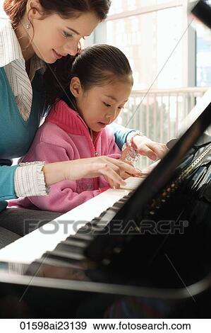 Stock Photo - Piano teacher and girl playing piano. Fotosearch