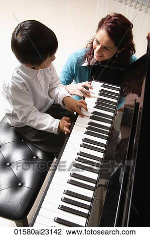 Piano teacher with little boy playing piano View Large Photo Image Stock Image - Piano teacher with little boy playing piano. Fotosearch