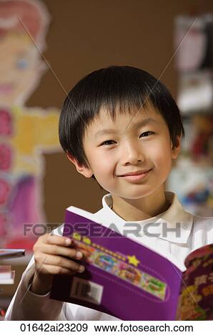 Schoolboy with book in hand in class looking at camera View Large Photo Image Stock Photo - Schoolboy with book in hand in class looking at camera. Fotosearch