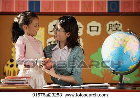Schoolgirl giving teacher an apple View Large Photo Image Stock Image - Schoolgirl giving teacher an apple. Fotosearch
