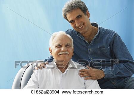 Senior man in chair, Adult son with hands on his shoulders View Large Photo Image Picture - Senior man in chair, Adult son with hands on his shoulders. Fotosearch