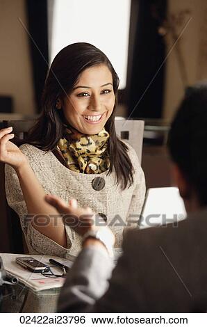Stock Photograph - smiling woman sitting with man and discussing. Fotosearch