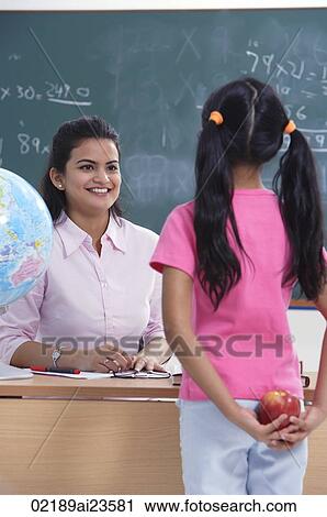Stock Image - student holding apple for teacher. Fotosearch