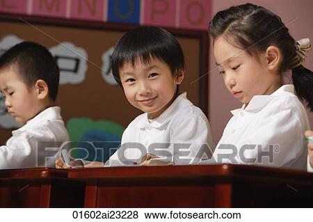 Stock Photo - Students in class, schoolboy smiling at camera. Fotosearch